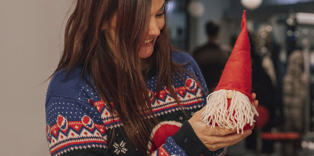 Ung kvinne med mørkt hår som viser frem en hjemmelaget nisse.